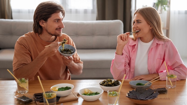 Foto grátis amigos de tiro médio comendo lanches de algas marinhas