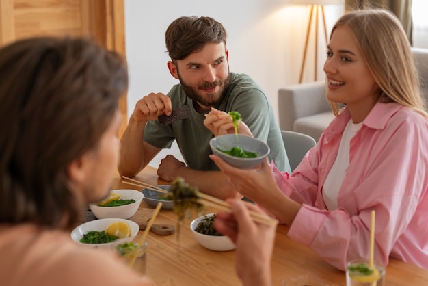 Foto grátis amigos de tiro médio comendo lanches de algas marinhas