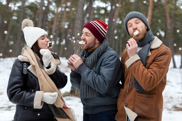 Amigos de tiro médio comendo marshmallows