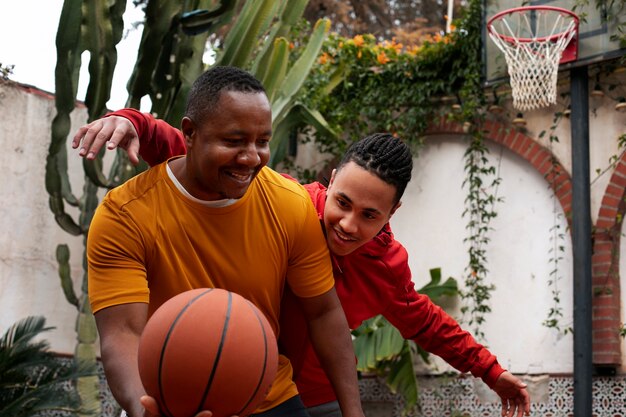 Amigos de tiro médio jogando basquete ao ar livre