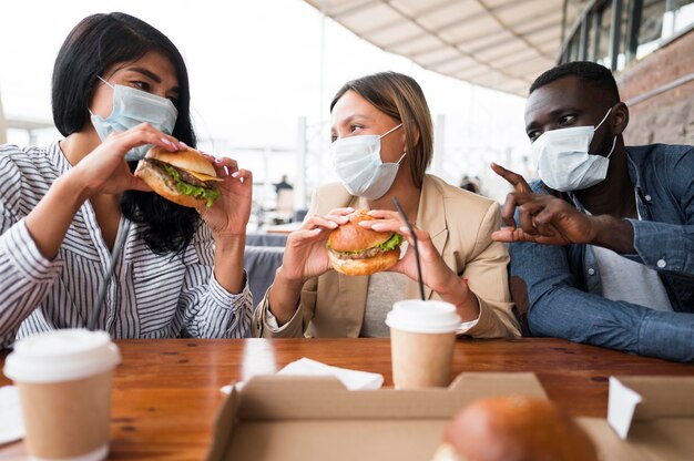 Amigos de tiro médio usando máscaras na mesa