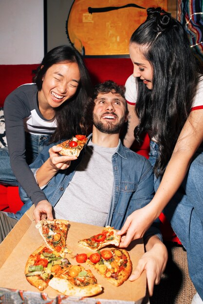 Amigos de tom médio a comer pizza.