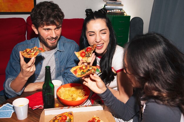 Amigos de tom médio a comer pizza.