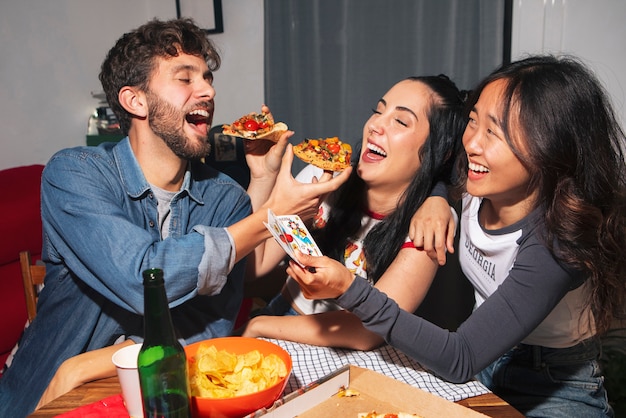 Amigos de tom médio a comer pizza.