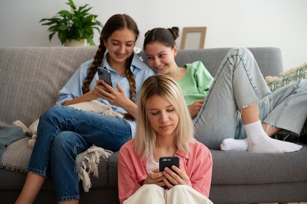 Amigos de vista frontal com smartphones dentro de casa