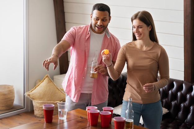 Amigos desfrutando de um jogo de beer pong em uma festa coberta