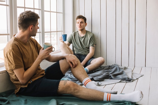 Foto grátis amigos, discutindo com o café da manhã sentado perto da janela