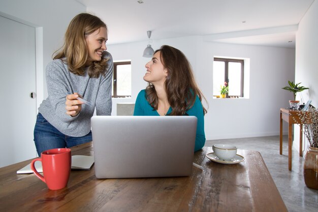 Amigos do sexo feminino alegres assistindo e discutindo o conteúdo de mídia