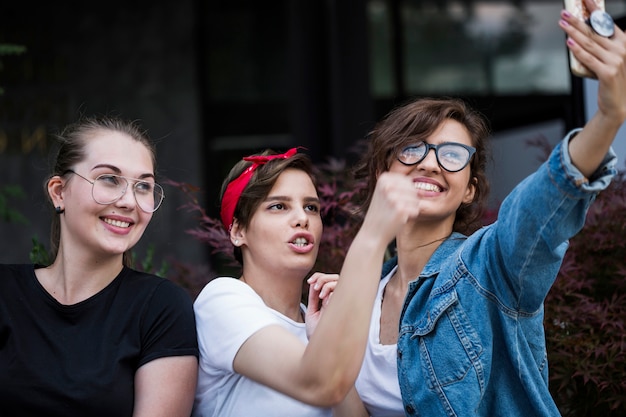 Amigos do sexo feminino alegres tomando selfie no parque