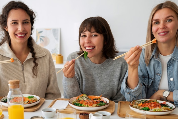 Foto grátis amigos do sexo feminino comendo prato de frutos do mar com salmão juntos