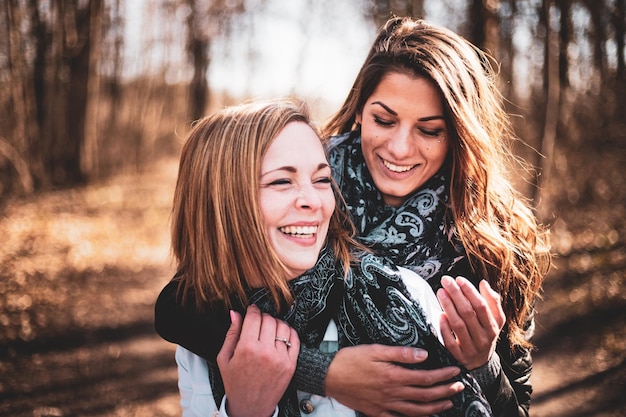 Amigos do sexo feminino posando abraçados sentados em um banco