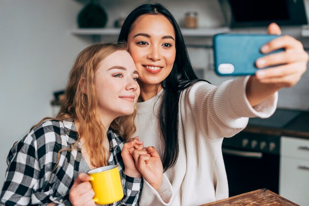 Amigos do sexo feminino tomando selfie em casa