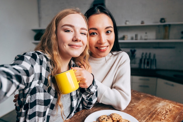 Amigos do sexo feminino tomando selfie na cozinha