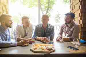 Foto grátis amigos do sexo masculino curtindo as bebidas com lanche no restaurante