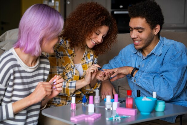 Amigos do sexo masculino e feminino fazendo uma manicure juntos