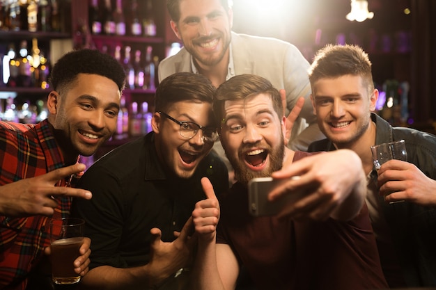 Amigos do sexo masculino felizes tomando selfie e bebendo cerveja