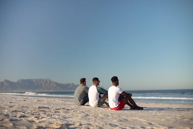 Amigos do sexo masculino relaxantes juntos na praia