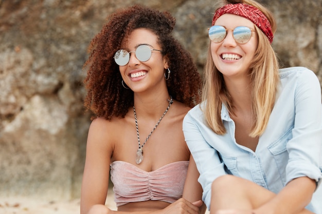 Foto grátis amigos elegantes sentados na praia