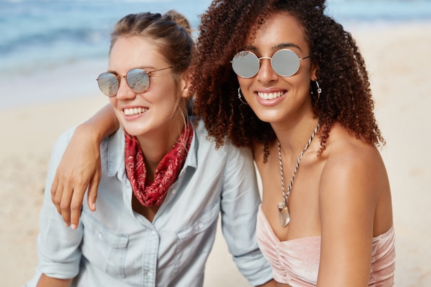 Foto grátis amigos elegantes sentados na praia