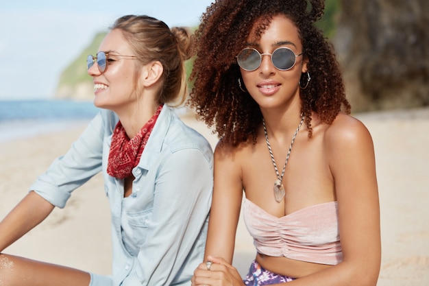 Foto grátis amigos elegantes sentados na praia