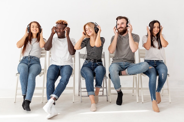 Amigos em cadeiras com fones de ouvido, ouvindo música