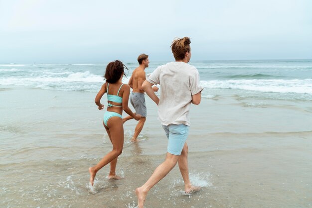 Amigos em tiro certeiro correndo na praia