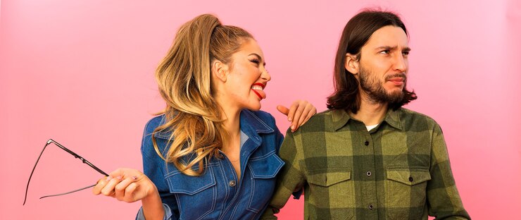 Foto grátis amigos engraçados passando o tempo juntos e se divertindo. mulher faz cara de maluca e cara nem olha pra ela. penteado e maquiagem modernos, terno jeans chique em seu corpo esguio