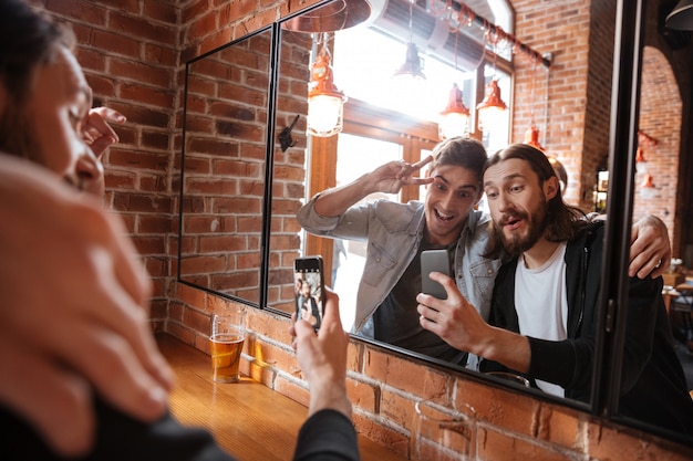 amigos fazendo foto perto do espelho no bar