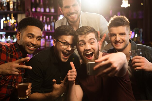 Amigos felizes a tirar selfies e a beber cerveja.