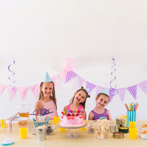 Foto grátis amigos felizes, aproveitando a festa de aniversário com lanche saboroso e bolo na mesa
