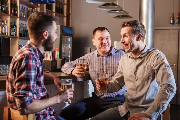 Amigos felizes bebendo cerveja no balcão no pub