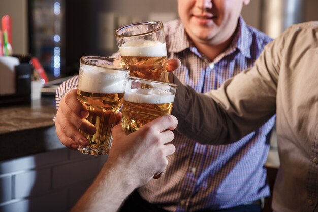 Amigos felizes bebendo cerveja no balcão no pub