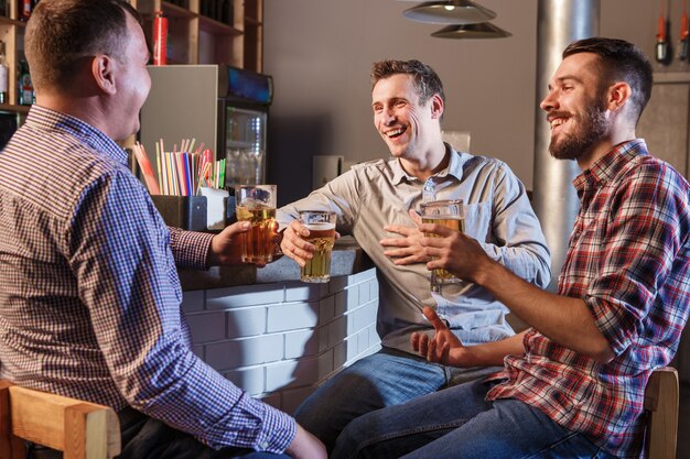 Amigos felizes bebendo cerveja no balcão no pub