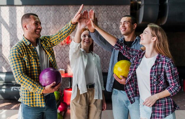 Amigos felizes com bolas de boliche em um clube de boliche