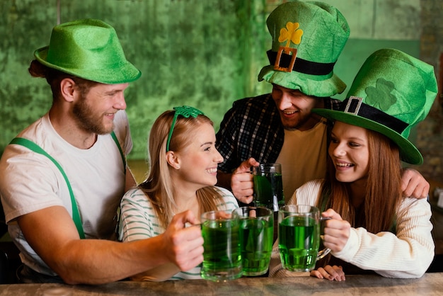 Amigos felizes comemorando juntos st. dia de patrick com bebidas