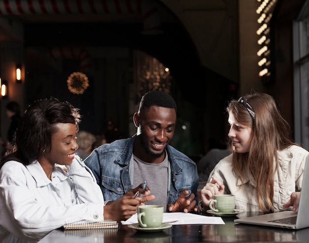 Amigos felizes trabalhando juntos dentro de casa