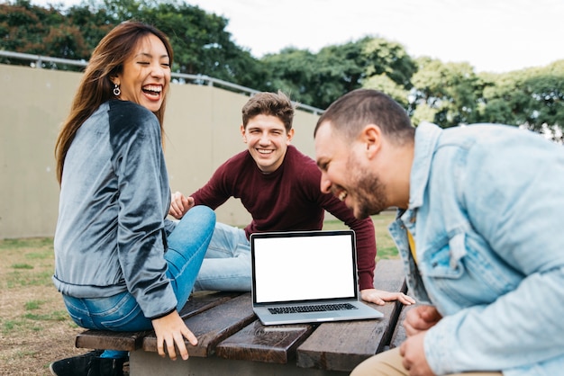 Foto grátis amigos multiétnicas se divertir no parque com laptop