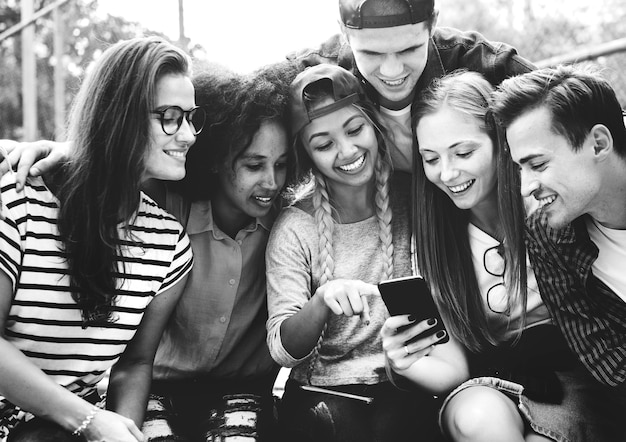 Amigos no parque procurando usando smartphones conceito de cultura jovem e milenar