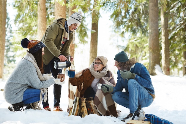 Amigos pela fogueira na floresta de inverno