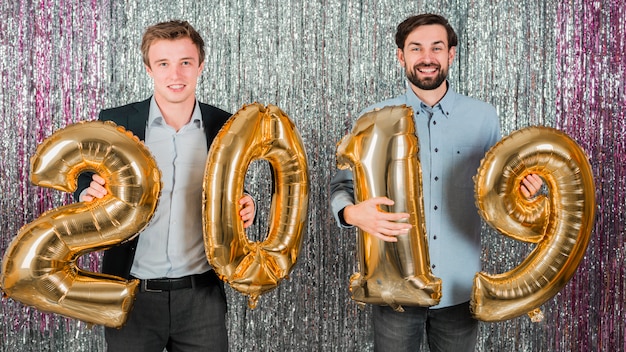 Amigos posando com balões de ouro em uma festa de ano novo