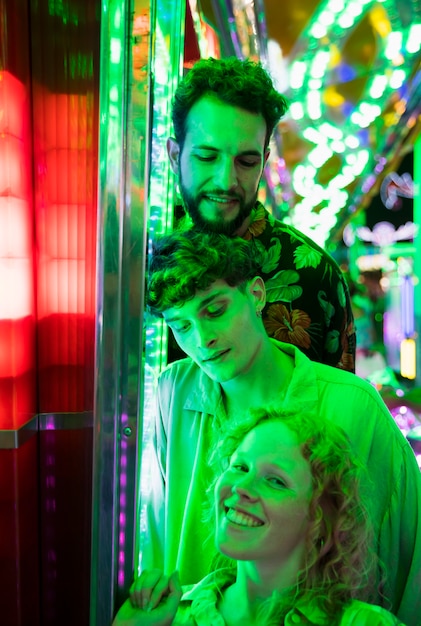 Amigos posando em luz verde no parque de diversões