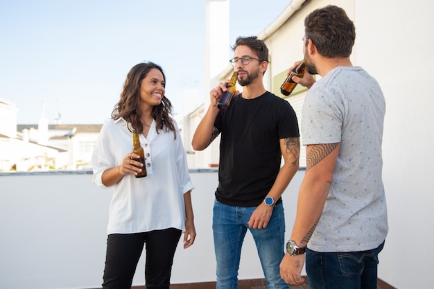 Amigos positivos relaxados curtindo a noite e bebendo cerveja