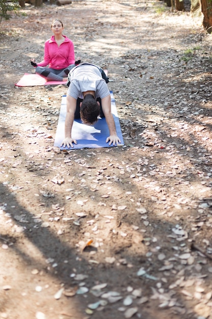 Amigos que relaxam no parque ao fazer exercícios de aquecimento