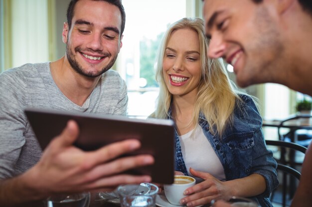 Amigos que usam a tabuleta digital ao mesmo tempo tem a chávena de café no cafÃ ©