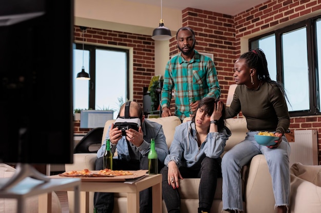 Amigos se reunindo na festa em casa para jogar videogame, sentindo-se tristes e frustrados por perder a competição com óculos de realidade virtual. grupo de pessoas se divertindo com atividade de lazer, jogabilidade perdida.