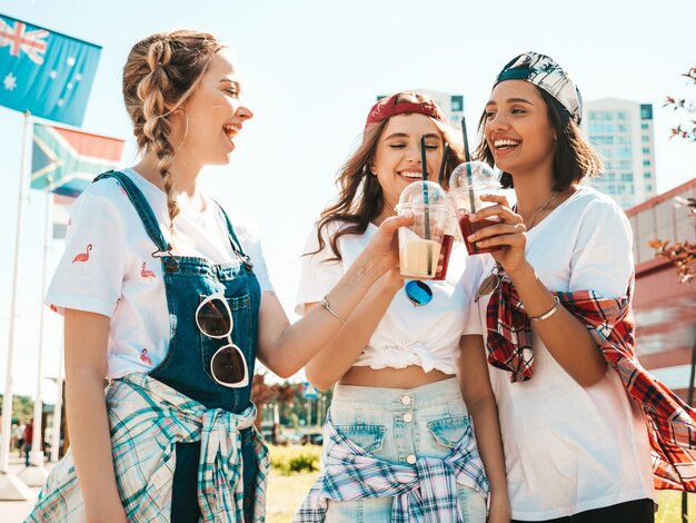 Amigos, segurando e bebendo smoothie de cocktail fresco bebem em copo de plástico com palha