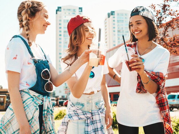 Amigos, segurando e bebendo smoothie de cocktail fresco bebem em copo de plástico com palha