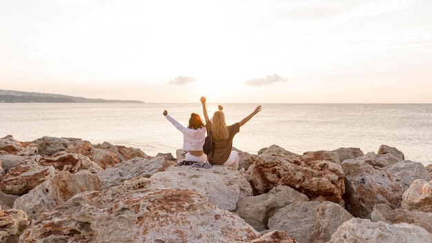 Foto grátis amigos sentados na pedra de costas