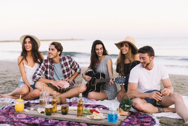 Amigos sentados na praia com guitarra