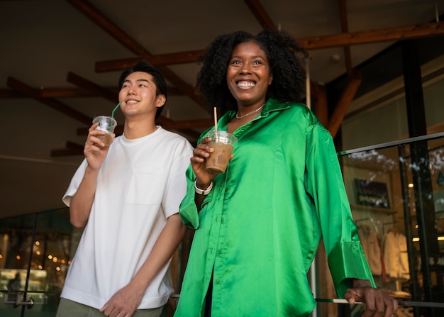 Amigos sorridentes de baixo ângulo segurando café gelado